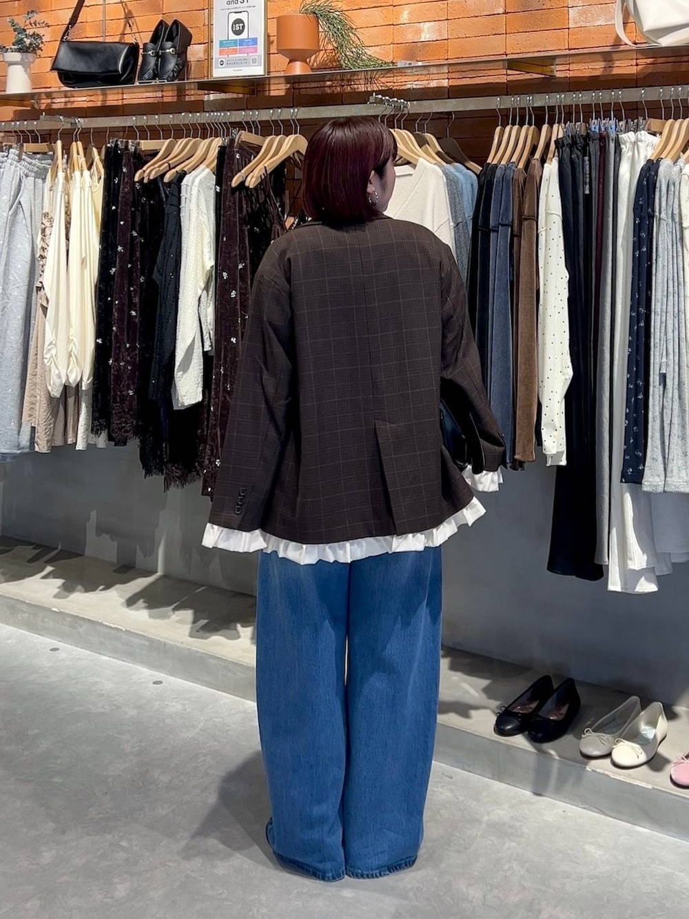 ブラック系のショルダーバッグ、ブルー系のデニムパンツ、ホワイト系のニット/セーターを着用したレディースの秋コーディネートの3枚目の写真