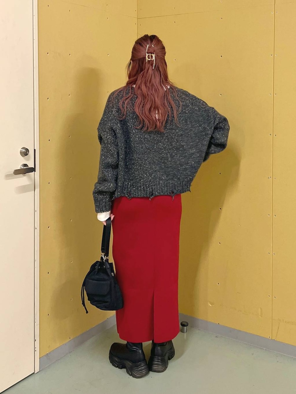 レッド系のスカート、ブラック系のショルダーバッグ、ブラック系のブーツを着用したレディースの秋コーディネートの3枚目の写真