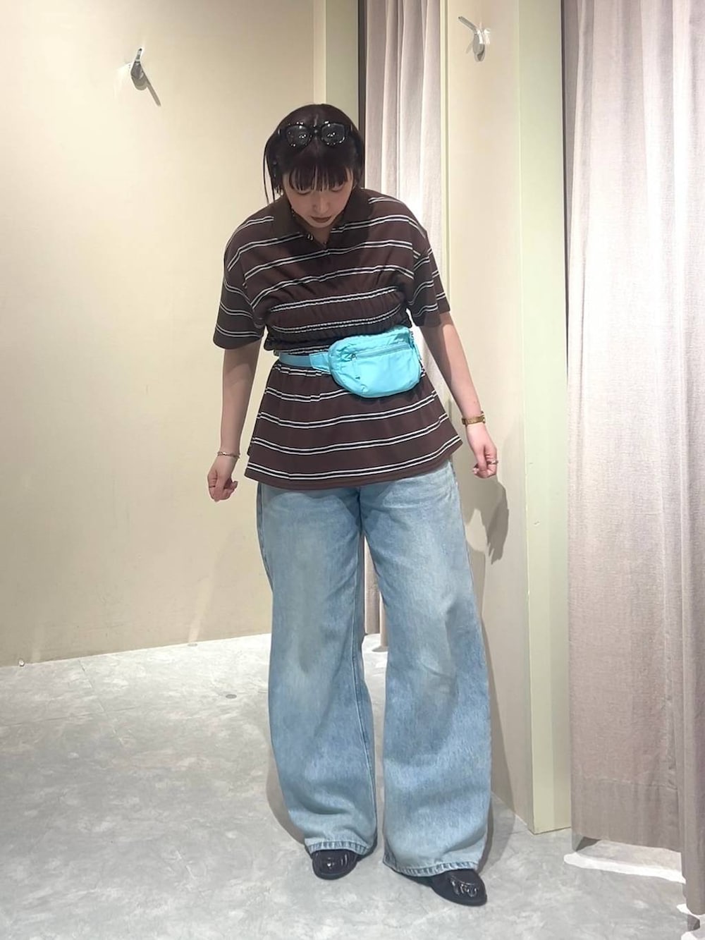 ブルー系のデニムパンツ、ブルー系のボディバッグ/ウエストポーチ、ブラウン系のローファーを着用したレディースの春コーディネートの5枚目の写真