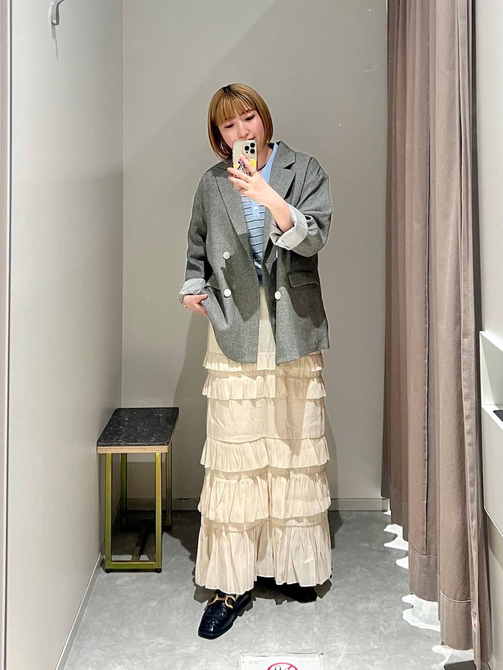 グレー系のテーラードジャケット、ホワイト系のスカート、ブルー系のポロシャツを着用したレディースの春コーディネートの8枚目の写真