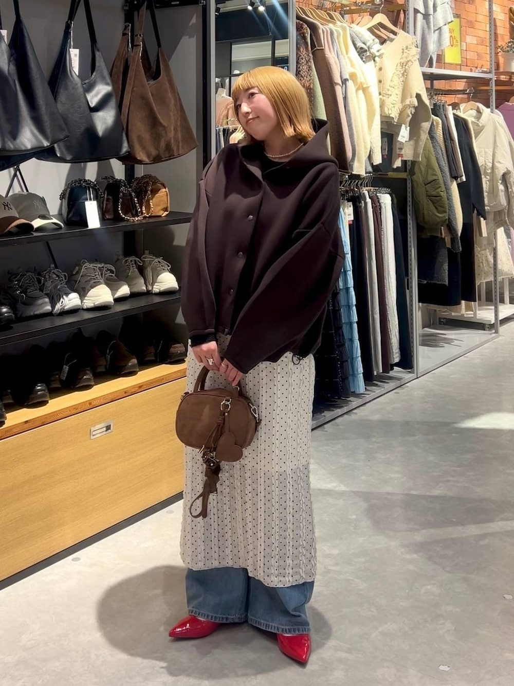 レッド系のパンプス、ブラウン系のボストンバッグ、ブルー系のデニムパンツを着用したレディースの春コーディネートの4枚目の写真