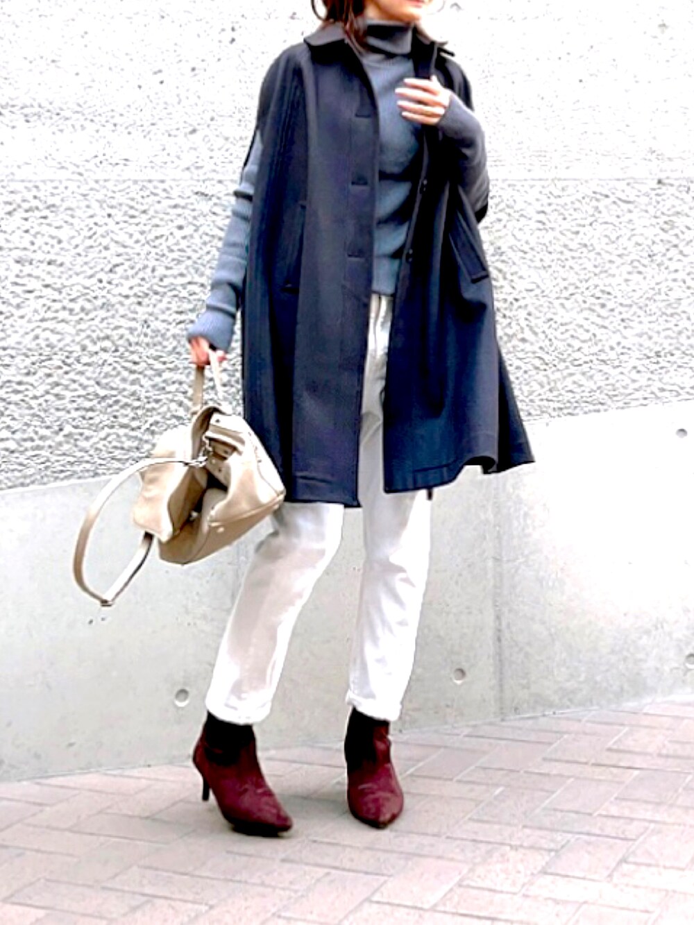 グレー系のニット/セーター、ブルー系のポンチョ、グレー系のハンドバッグを着用したレディースの秋コーディネートの2枚目の写真