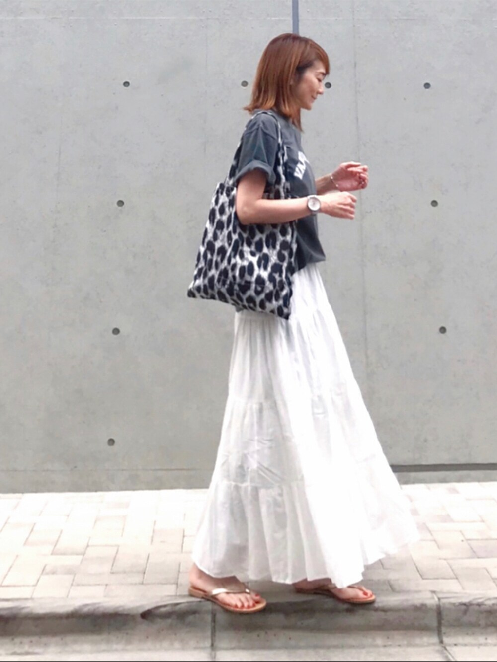 ホワイト系のスカート、グレー系のトートバッグ、ゴールド系のサンダルを着用したレディースの春コーディネートの5枚目の写真