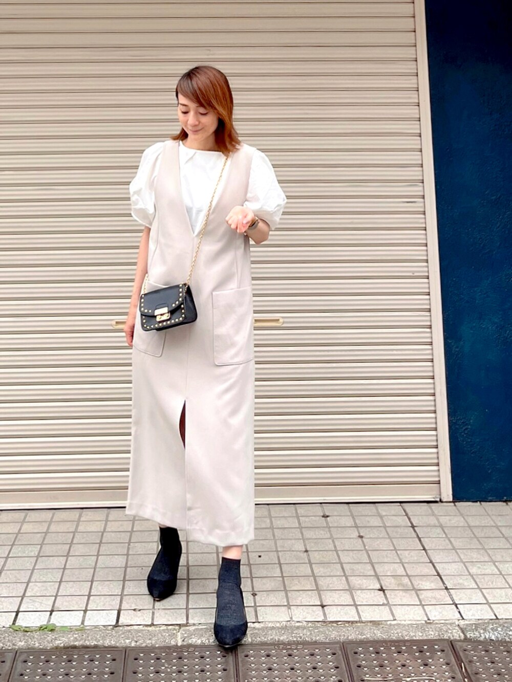 ベージュ系のワンピース、ブラック系のパンプス、ブラック系のバッグを着用したレディースの夏コーディネートの2枚目の写真