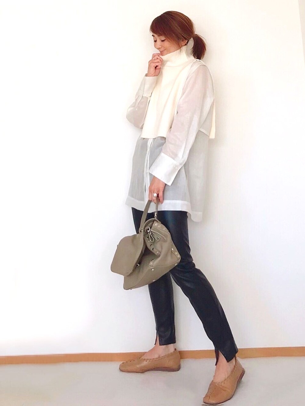 グレー系のハンドバッグ、ホワイト系のニット/セーター、ホワイト系のシャツ/ブラウスを着用したレディースの冬コーディネートの2枚目の写真