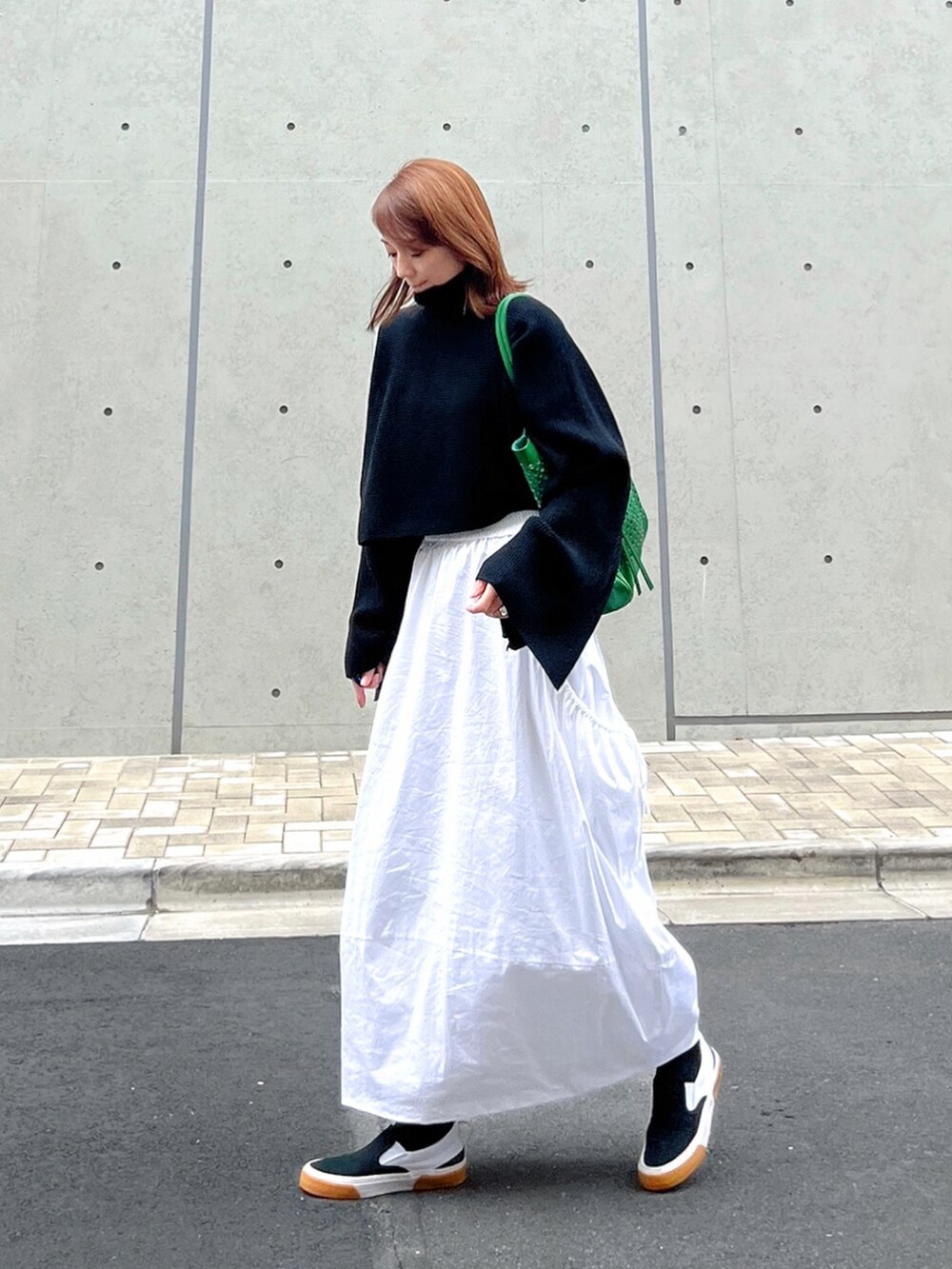 ブラック系のニット/セーター、ホワイト系のスカート、ブラック系のスニーカーを着用したレディースの秋コーディネートの2枚目の写真