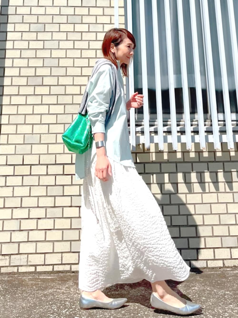 グリーン系のシャツ/ブラウス、ホワイト系のスカート、グリーン系のショルダーバッグを着用したレディースの春コーディネートの3枚目の写真