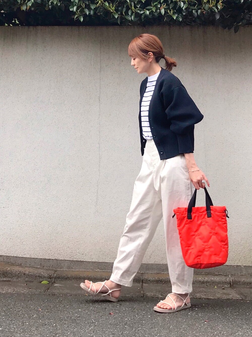 オレンジ系のトートバッグ、ブルー系のカーディガン/ボレロ、ブラック系のTシャツ/カットソーを着用したレディースの春コーディネートの2枚目の写真