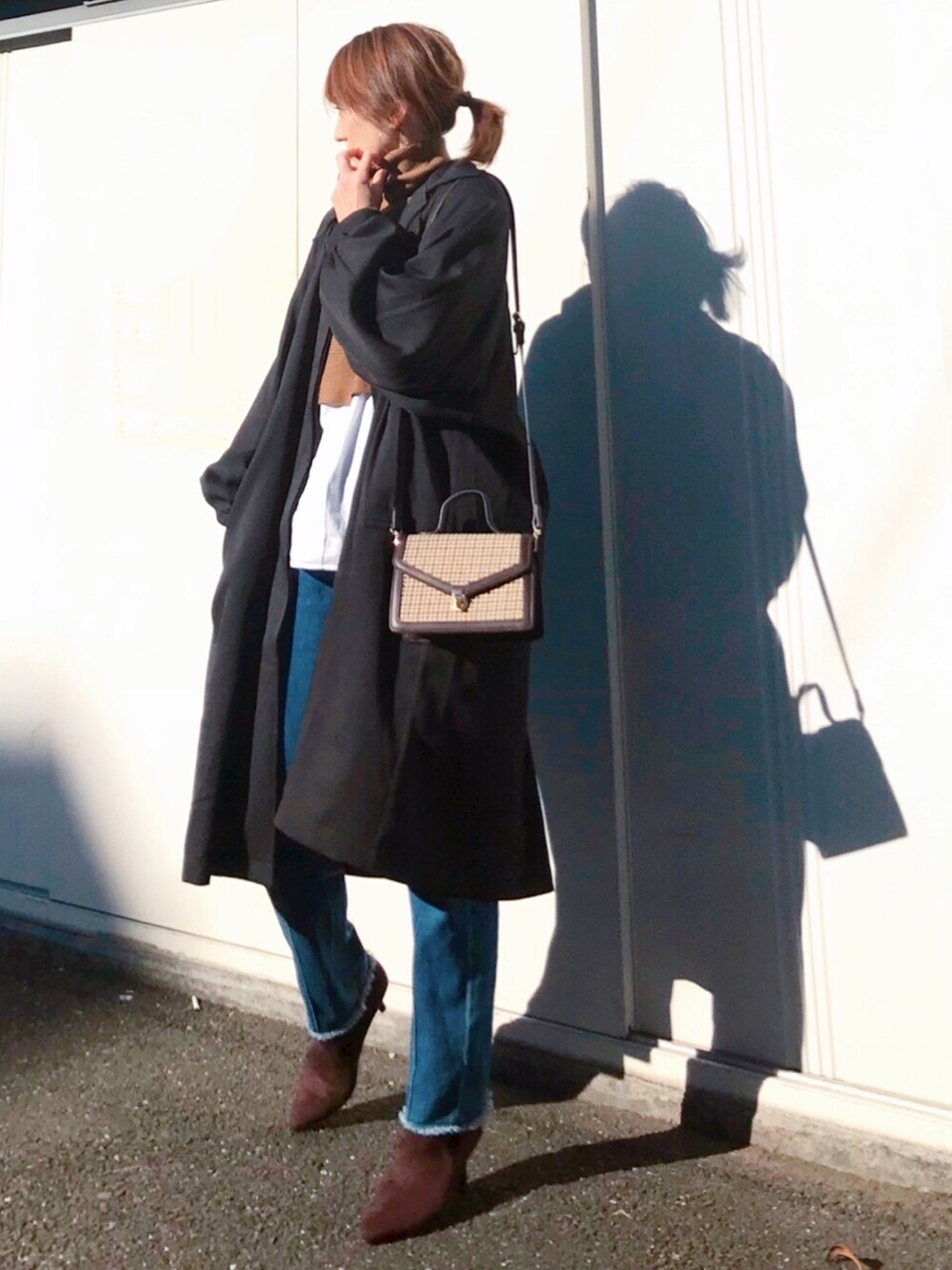 ブラウン系のショルダーバッグ、ブラウン系のブーツ、ブラック系のステンカラーコートを着用したレディースの冬コーディネートの2枚目の写真