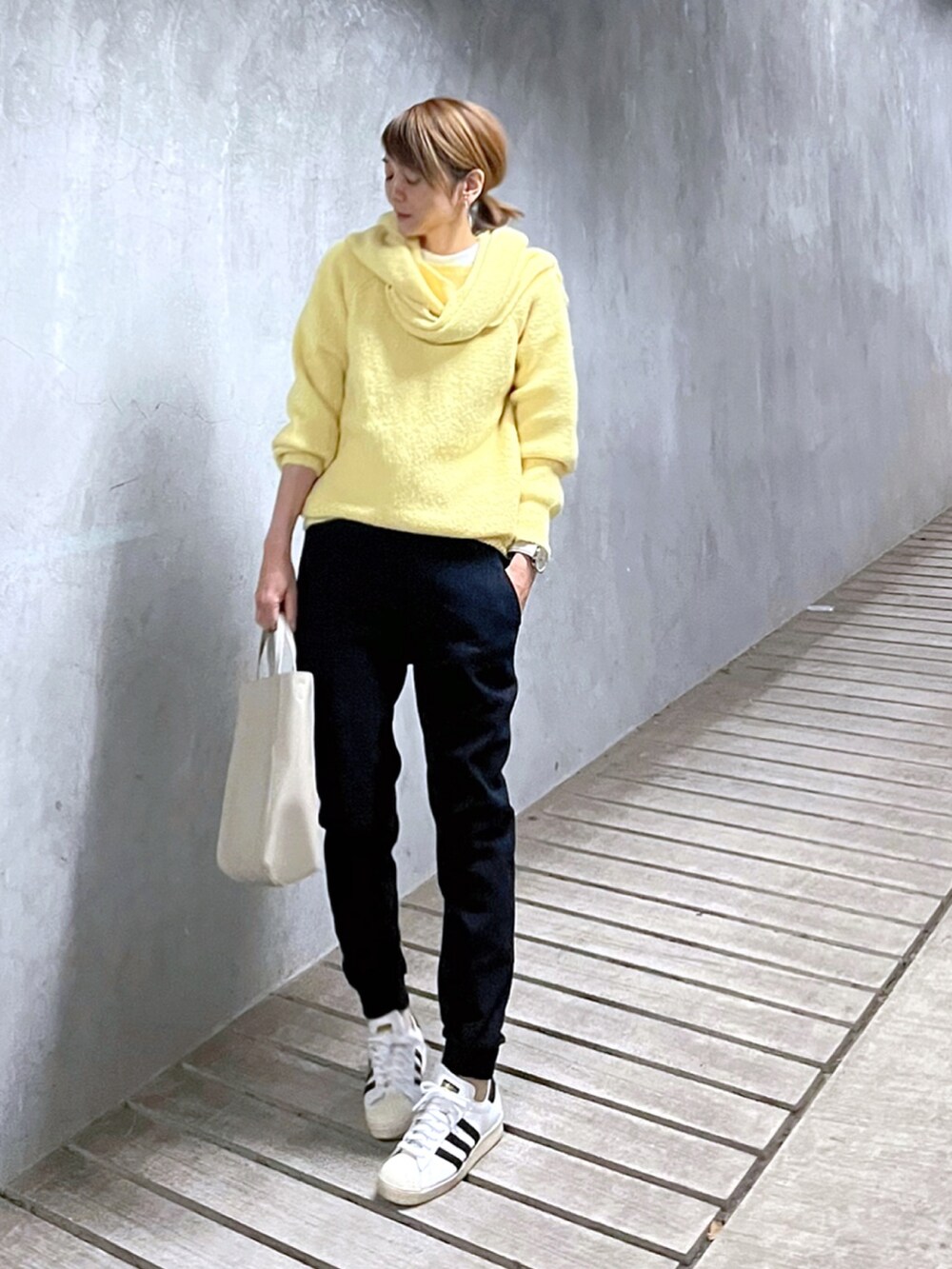 ホワイト系のトートバッグ、ホワイト系のスニーカー、イエロー系のニット/セーターを着用したレディースの冬コーディネートの2枚目の写真