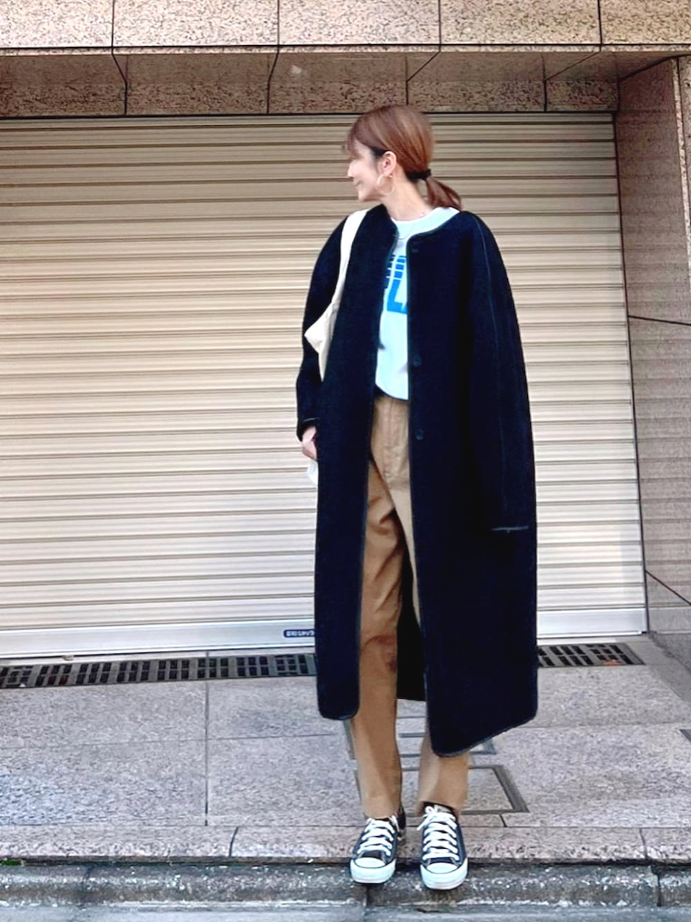 ブラック系のスニーカー、ブラック系のピーコート、イエロー系のチノパンツを着用したレディースの冬コーディネートの2枚目の写真