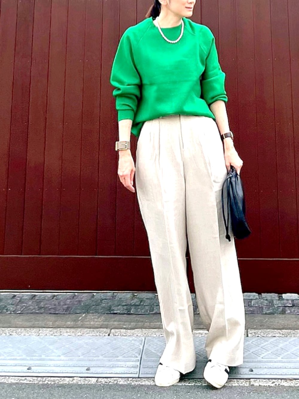 グリーン系のニット/セーター、ベージュ系のその他パンツ、ブラウン系のハンドバッグを着用したレディースの秋コーディネートの2枚目の写真