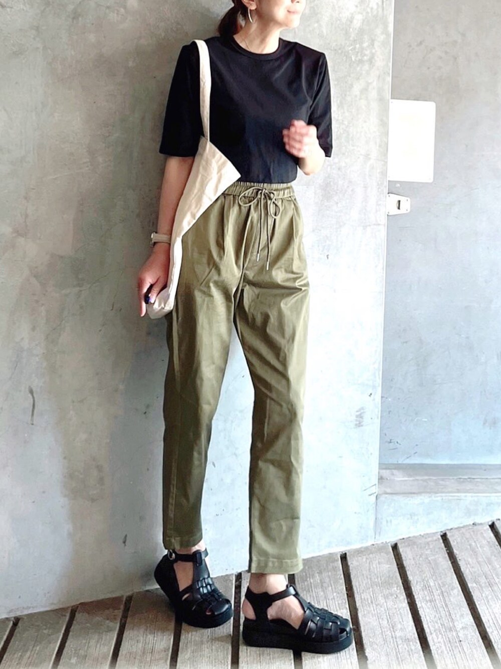 ブラック系のTシャツ/カットソー、ブラック系のサンダル、ホワイト系のトートバッグを着用したレディースの秋コーディネートの3枚目の写真