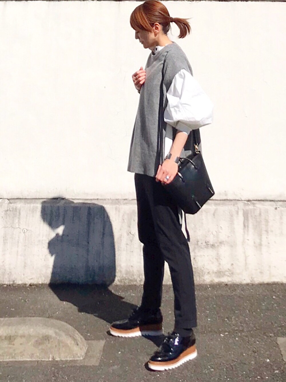 グレー系のベスト、ホワイト系のシャツ/ブラウス、ブラック系のトートバッグを着用したレディースの冬コーディネートの3枚目の写真