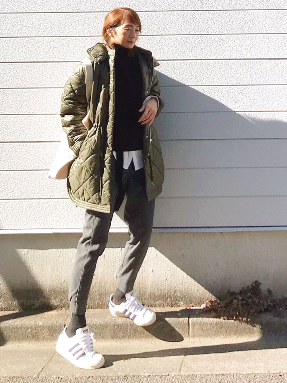 ブラック系のニット/セーター、ホワイト系のトートバッグ、ホワイト系のスニーカーを着用したレディースの冬コーディネートの2枚目の写真