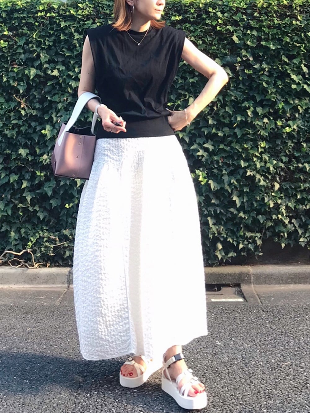ホワイト系のスカート、ブラック系のTシャツ/カットソー、ホワイト系のサンダルを着用したレディースの夏コーディネートの3枚目の写真