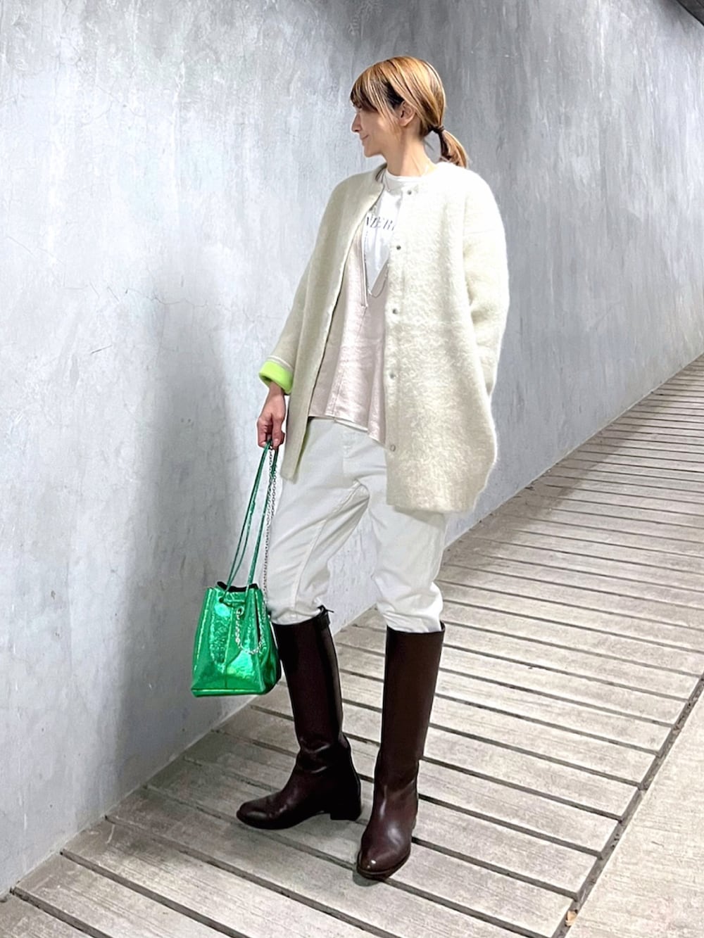 ホワイト系のカーディガン/ボレロ、グリーン系のショルダーバッグ、ブラウン系のブーツを着用したレディースの冬コーディネートの2枚目の写真