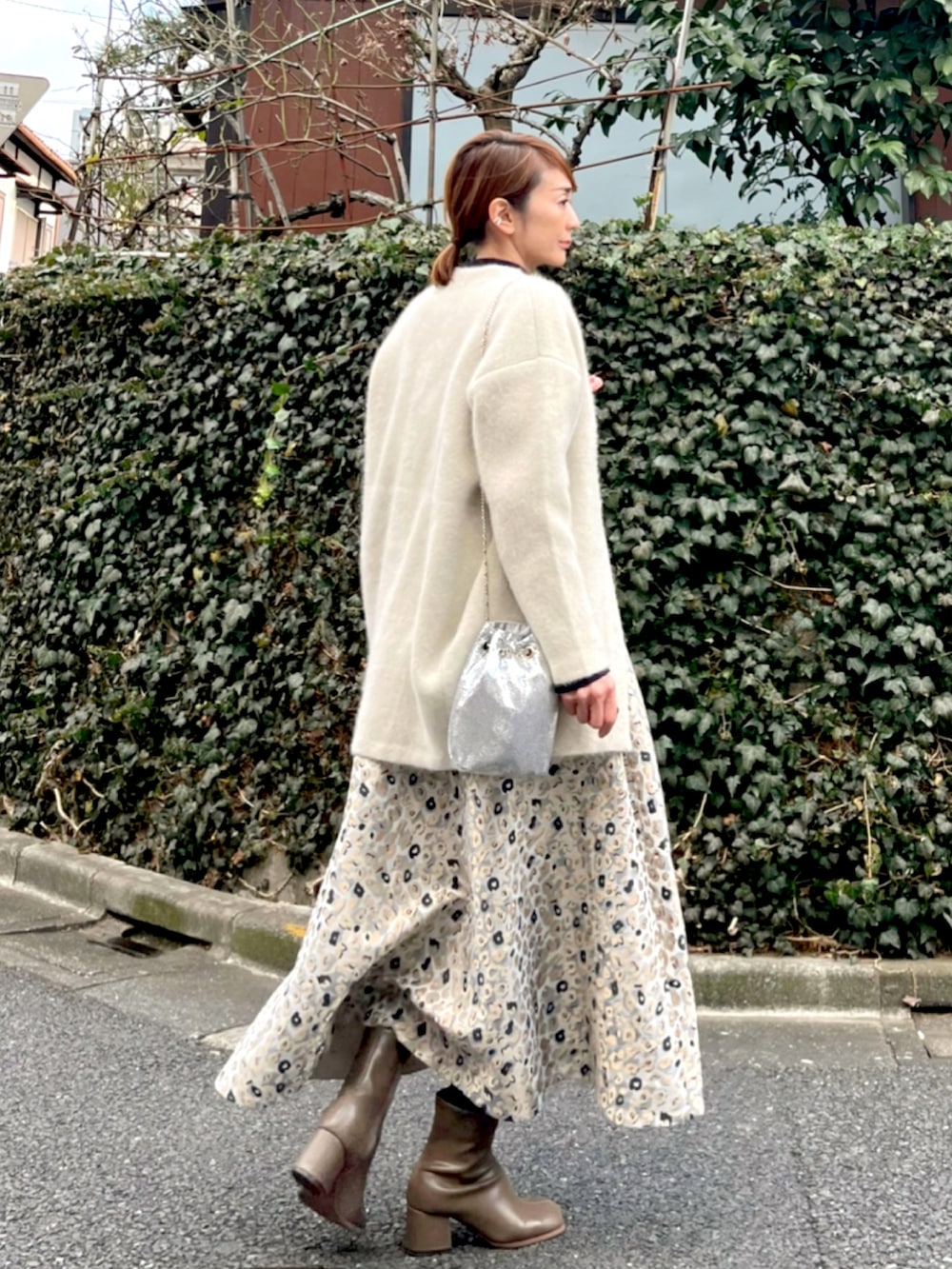 ベージュ系のスカート、ブルー系のニット/セーター、ホワイト系のカーディガン/ボレロを着用したレディースの冬コーディネートの2枚目の写真