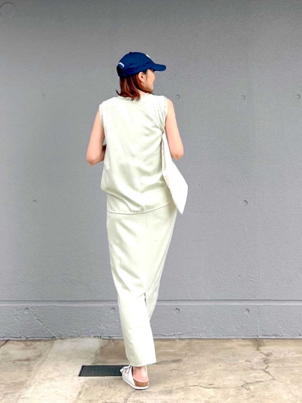 ホワイト系のサンダル、グリーン系のタンクトップ、グリーン系のスカートを着用したレディースの夏コーディネートの3枚目の写真