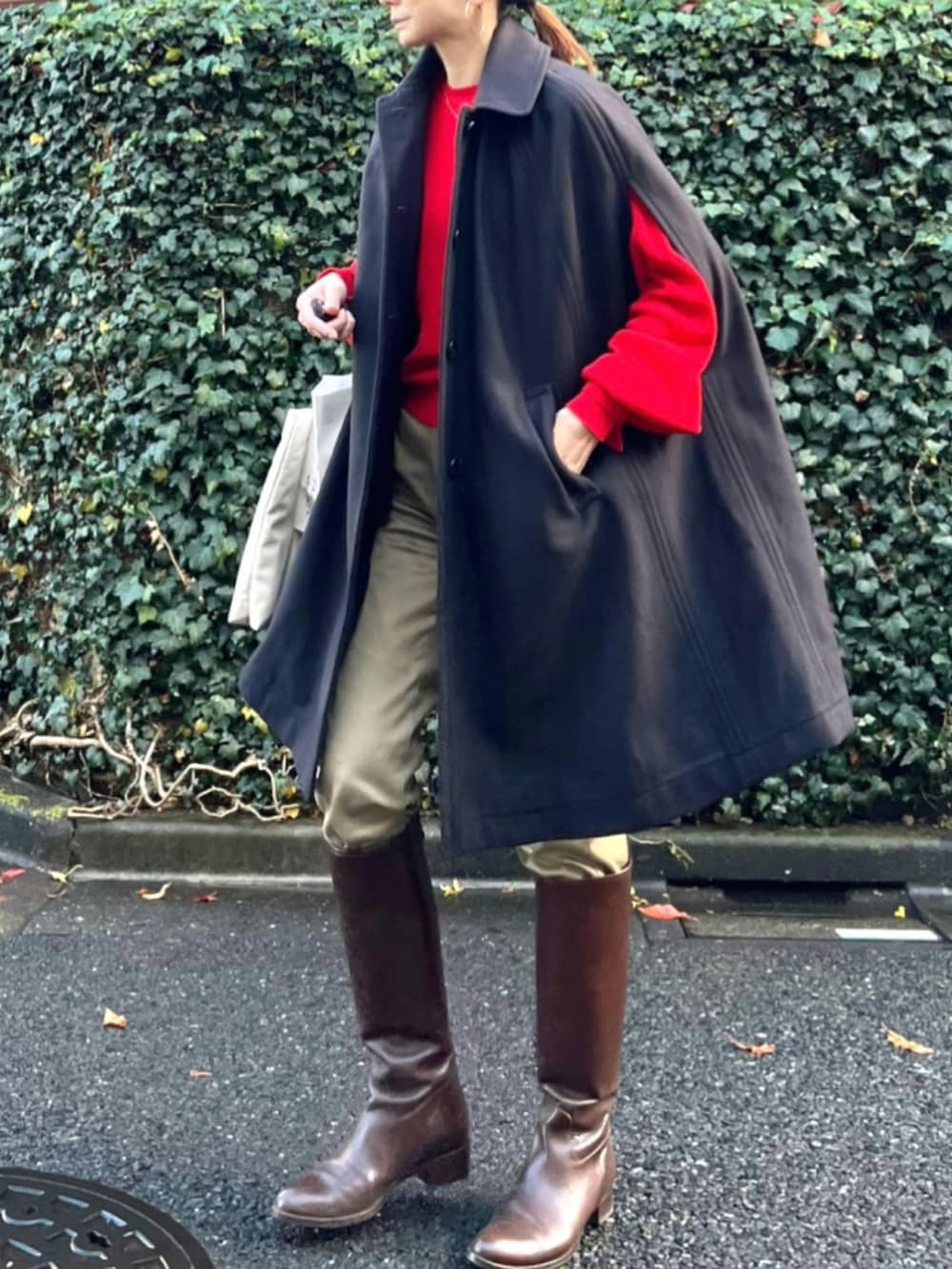 レッド系のニット/セーター、ブルー系のポンチョ、ベージュ系のその他パンツを着用したレディースの冬コーディネートの2枚目の写真