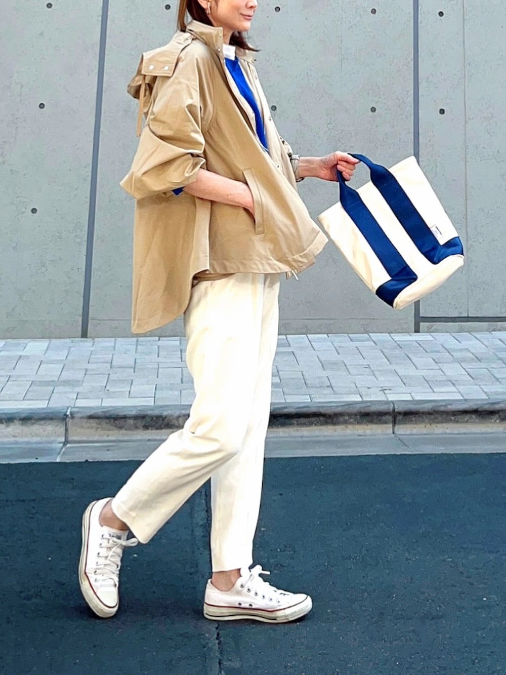 イエロー系のマウンテンパーカー、ブルー系のニット/セーター、ホワイト系のその他パンツを着用したレディースの春コーディネートの2枚目の写真