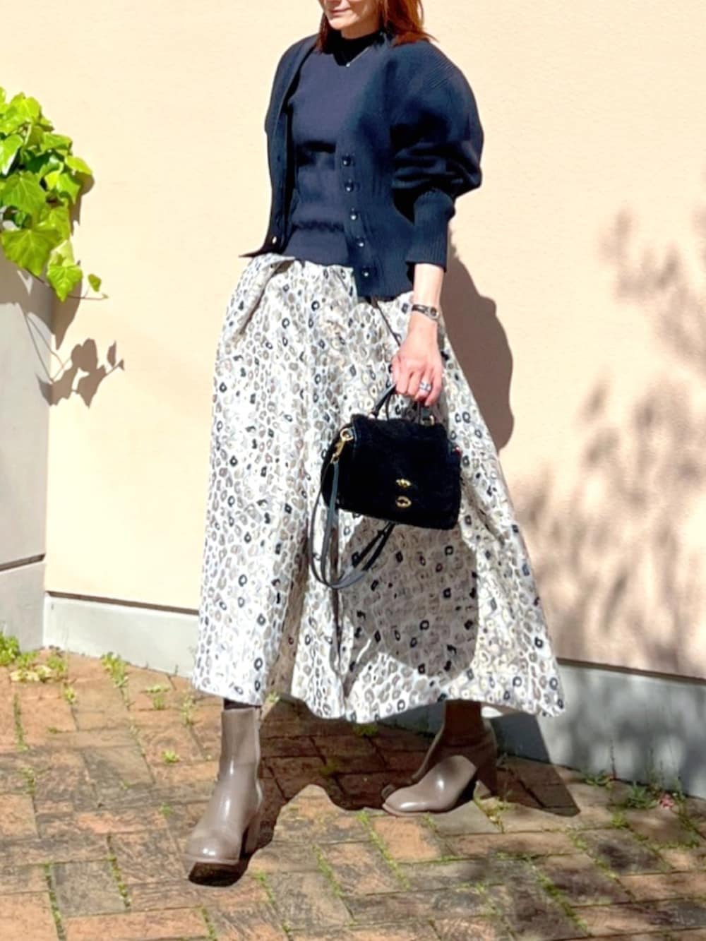 ベージュ系のスカート、ブルー系のニット/セーター、ブルー系のカーディガン/ボレロを着用したレディースの春コーディネートの2枚目の写真