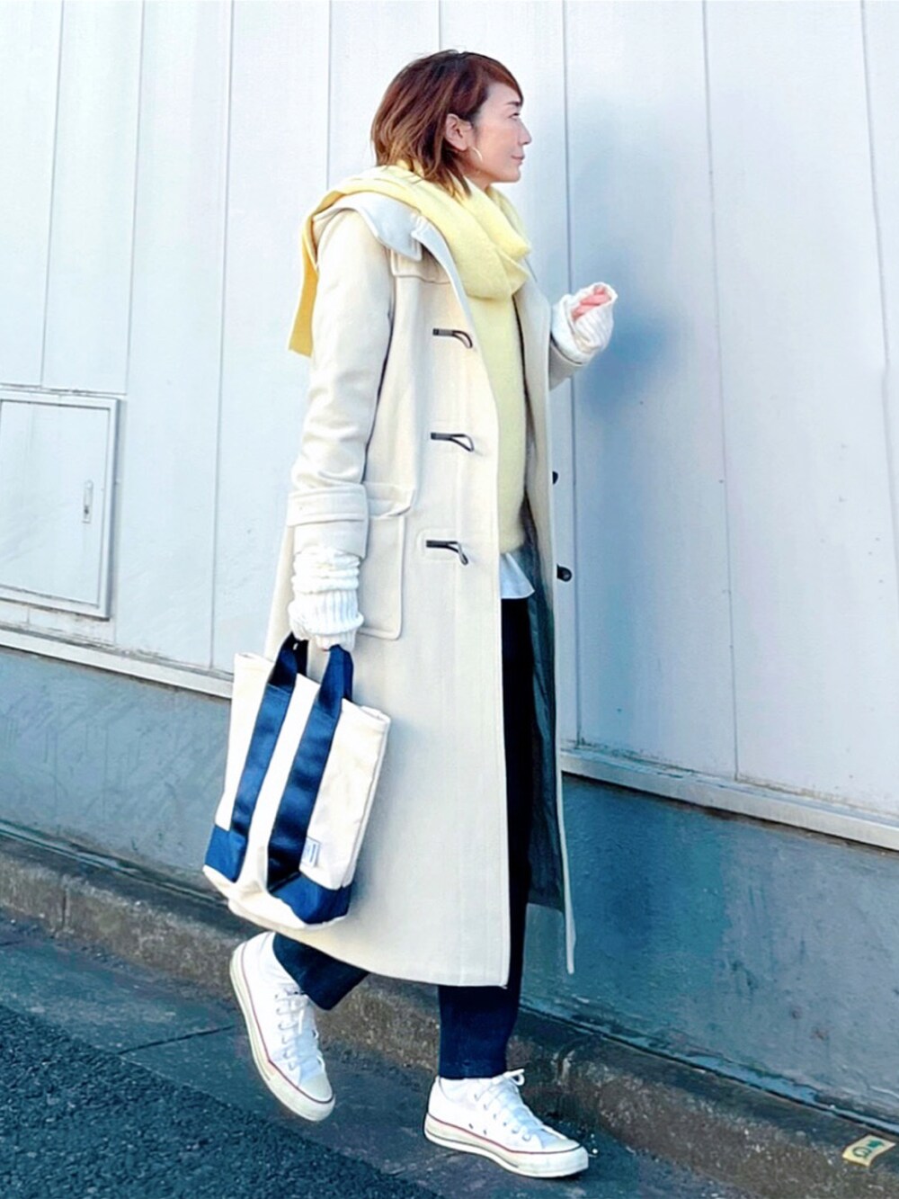 ホワイト系のスニーカー、ホワイト系のトートバッグ、ブルー系のデニムパンツを着用したレディースの冬コーディネートの4枚目の写真