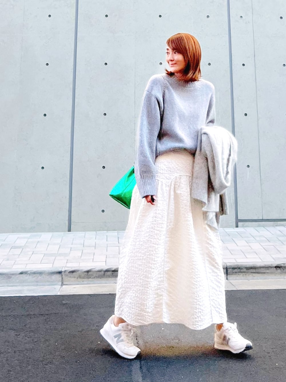 グリーン系のショルダーバッグ、グレー系のカーディガン/ボレロ、ホワイト系のスカートを着用したレディースの秋コーディネートの2枚目の写真