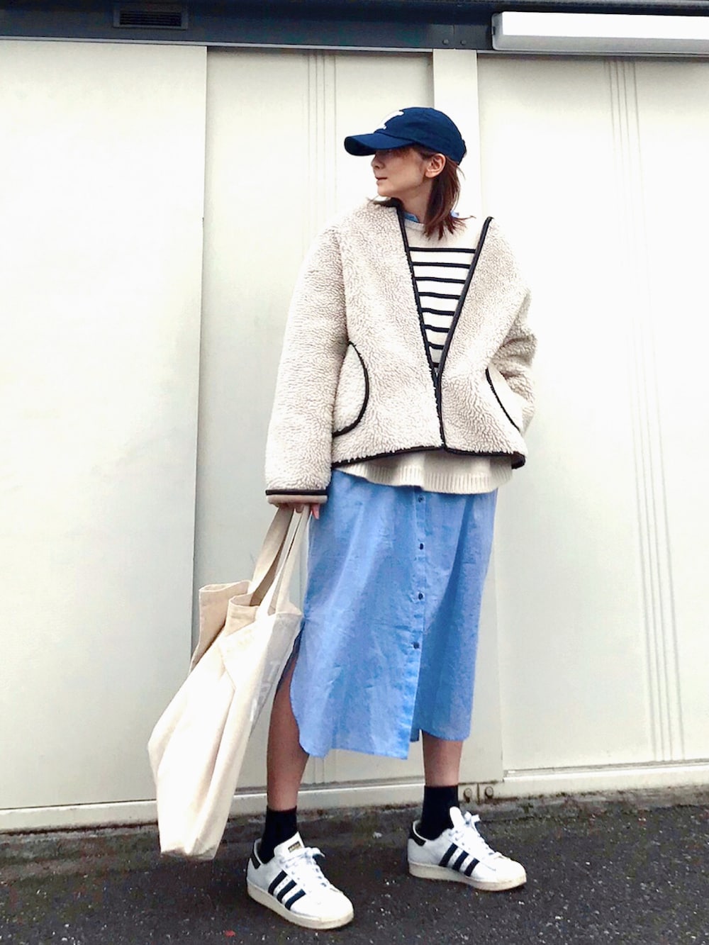 ホワイト系のブルゾン、ブルー系のシャツワンピース、ホワイト系のトートバッグを着用したレディースの冬コーディネートの2枚目の写真