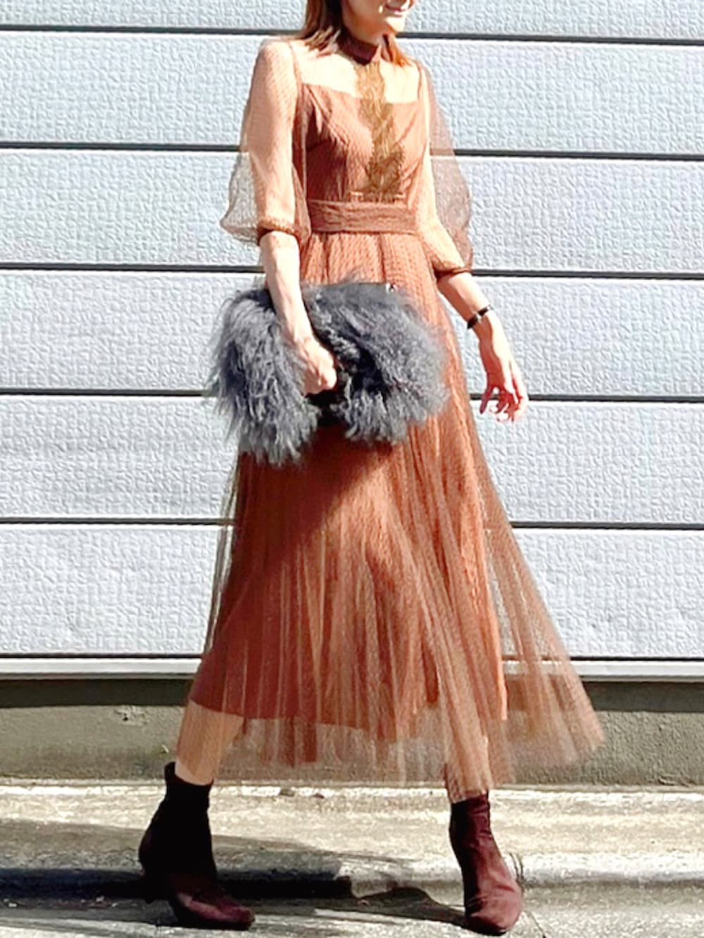 ブラウン系のドレス、ブラウン系のブーツ、グレー系のクラッチバッグを着用したレディースの秋コーディネートの3枚目の写真