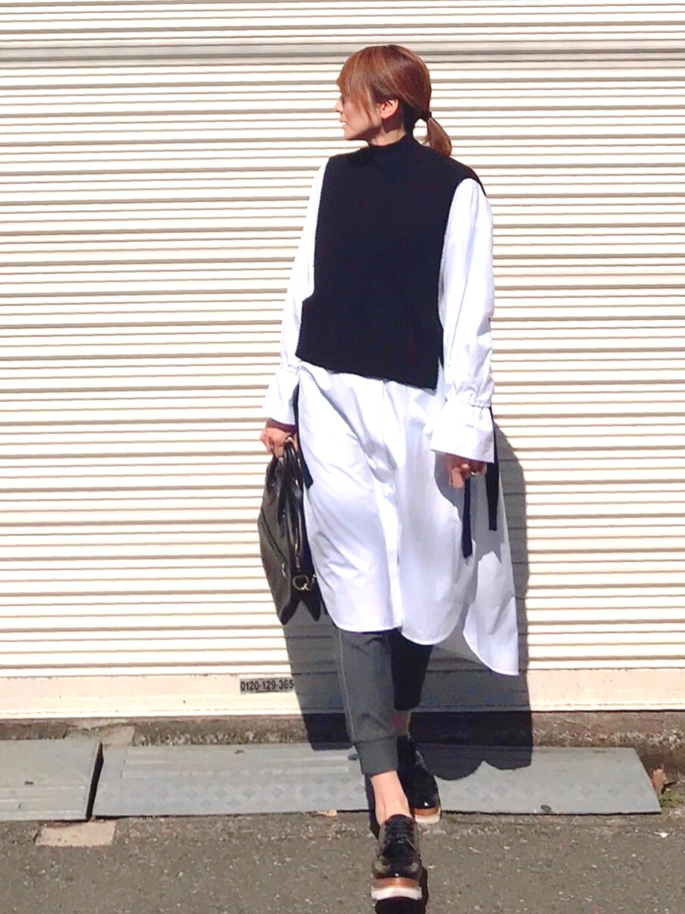 ホワイト系のワンピース、ブラック系のショルダーバッグ、ブラック系のニット/セーターを着用したレディースの春コーディネートの2枚目の写真