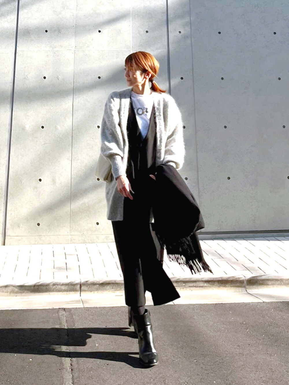 グレー系のカーディガン/ボレロ、ブラック系のワンピース、ブラック系のブーツを着用したレディースの冬コーディネートの2枚目の写真