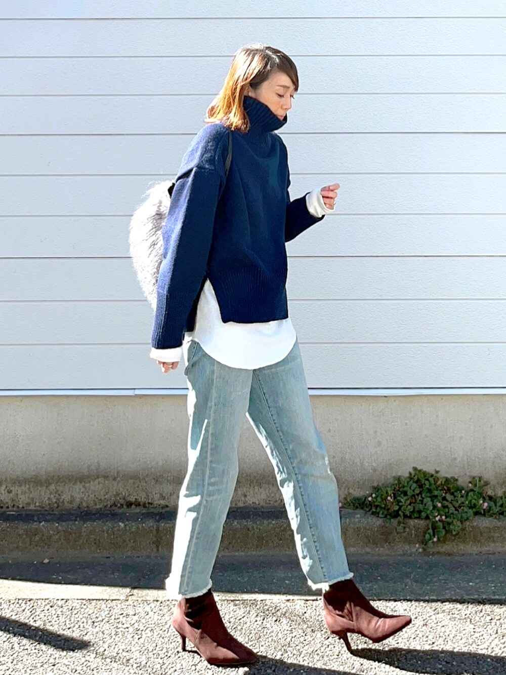 ブルー系のニット/セーター、ブルー系のデニムパンツを着用したレディースの秋コーディネートの4枚目の写真