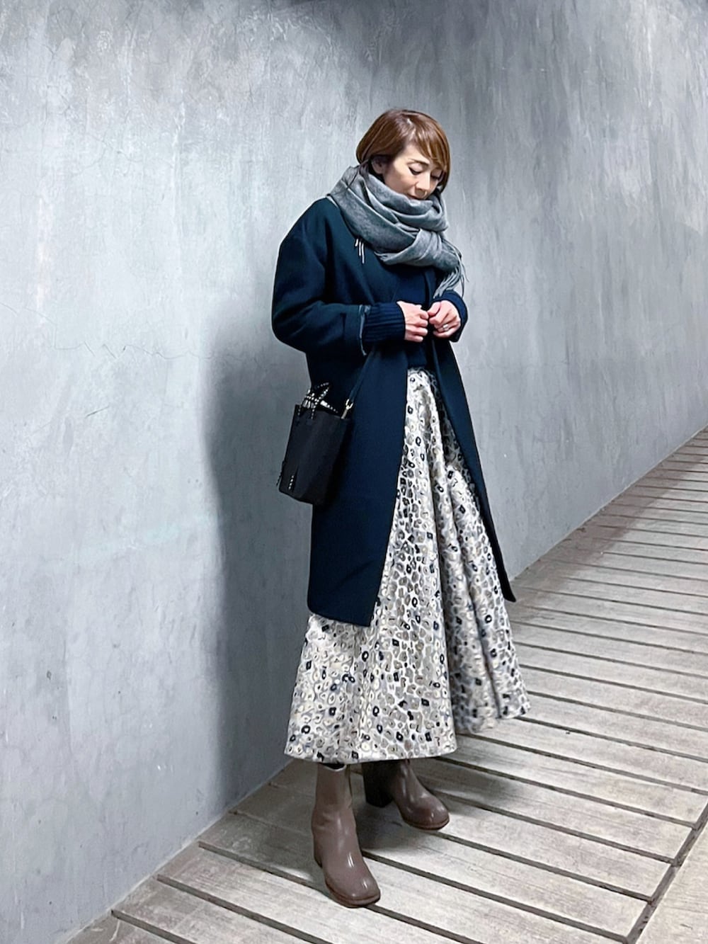 ベージュ系のスカート、ブルー系のニット/セーター、ベージュ系のブーツを着用したレディースの冬コーディネートの2枚目の写真