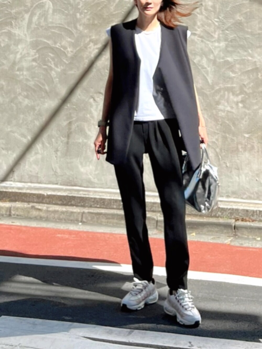 シルバー系のボストンバッグ、ホワイト系のスニーカー、ブラック系のその他パンツを着用したレディースの秋コーディネートの2枚目の写真