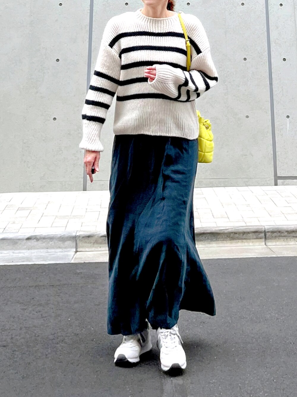 ホワイト系のニット/セーター、グレー系のスカート、ホワイト系のスニーカーを着用したレディースの冬コーディネートの2枚目の写真