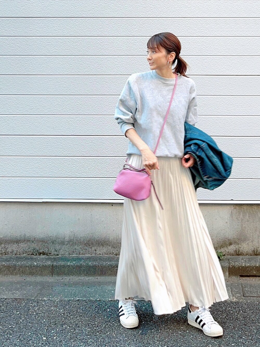 ホワイト系のスカート、ホワイト系のスニーカー、ピンク系のショルダーバッグを着用したレディースの秋コーディネートの3枚目の写真