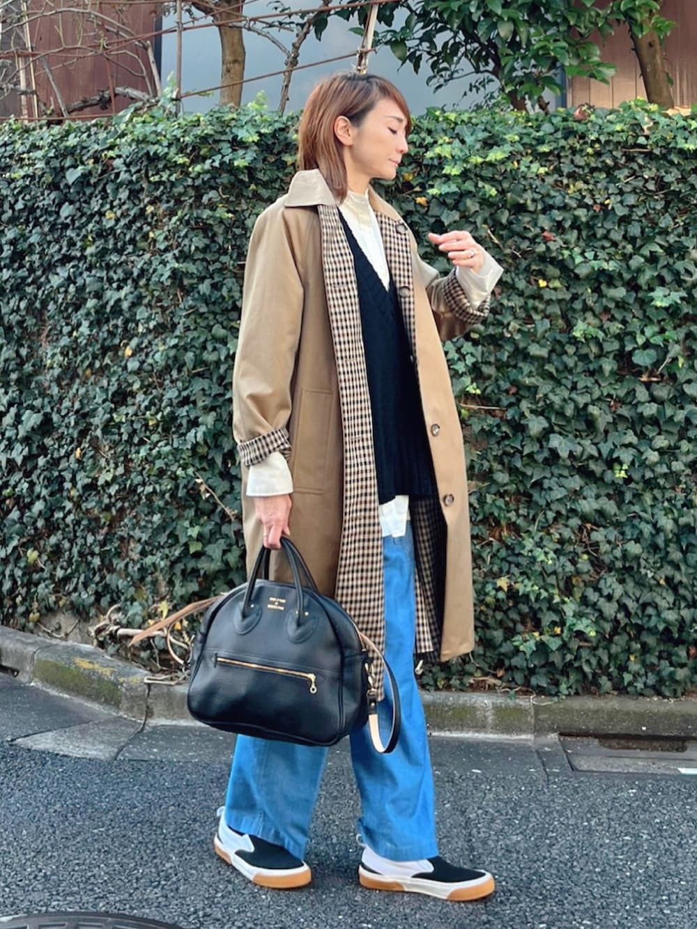 ベージュ系のステンカラーコート、ブルー系のその他パンツ、ブラック系のショルダーバッグを着用したレディースの冬コーディネートの3枚目の写真