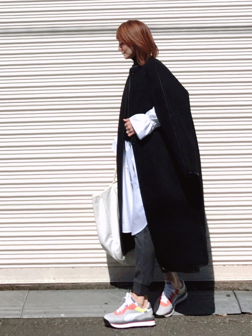 ブラック系のピーコート、ホワイト系のワンピース、ホワイト系のトートバッグを着用したレディースの冬コーディネートの2枚目の写真