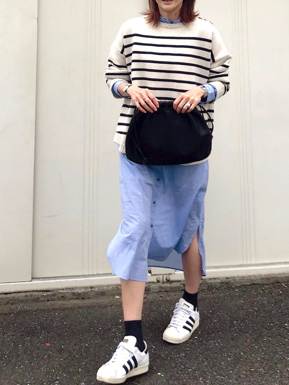 ホワイト系のニット/セーター、ブラウン系のハンドバッグ、ブルー系のシャツワンピースを着用したレディースの冬コーディネートの2枚目の写真