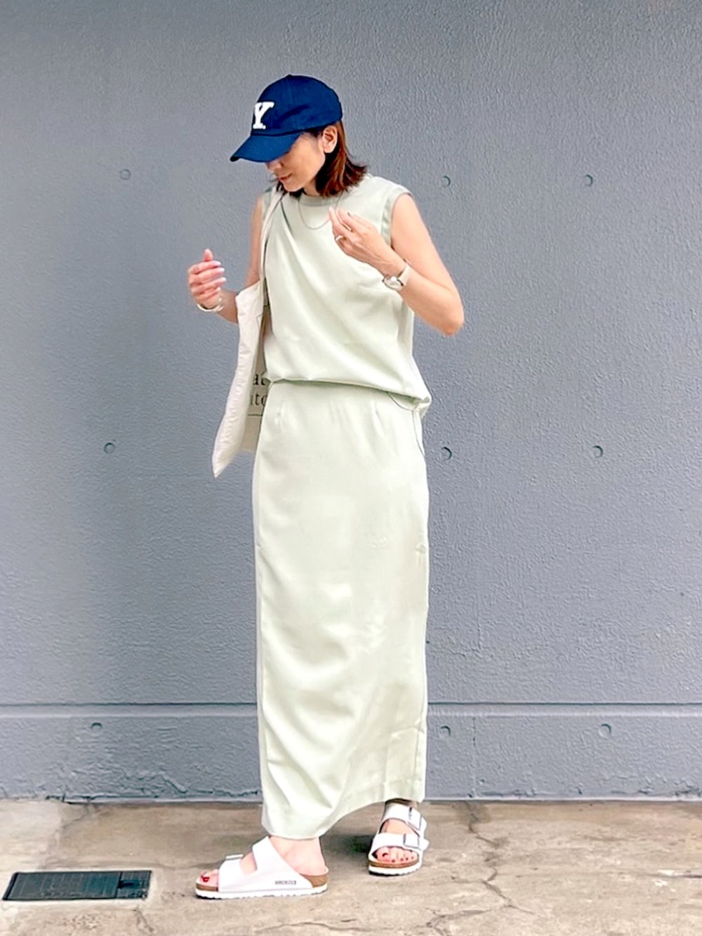 ホワイト系のサンダル、グリーン系のタンクトップ、グリーン系のスカートを着用したレディースの夏コーディネートの4枚目の写真