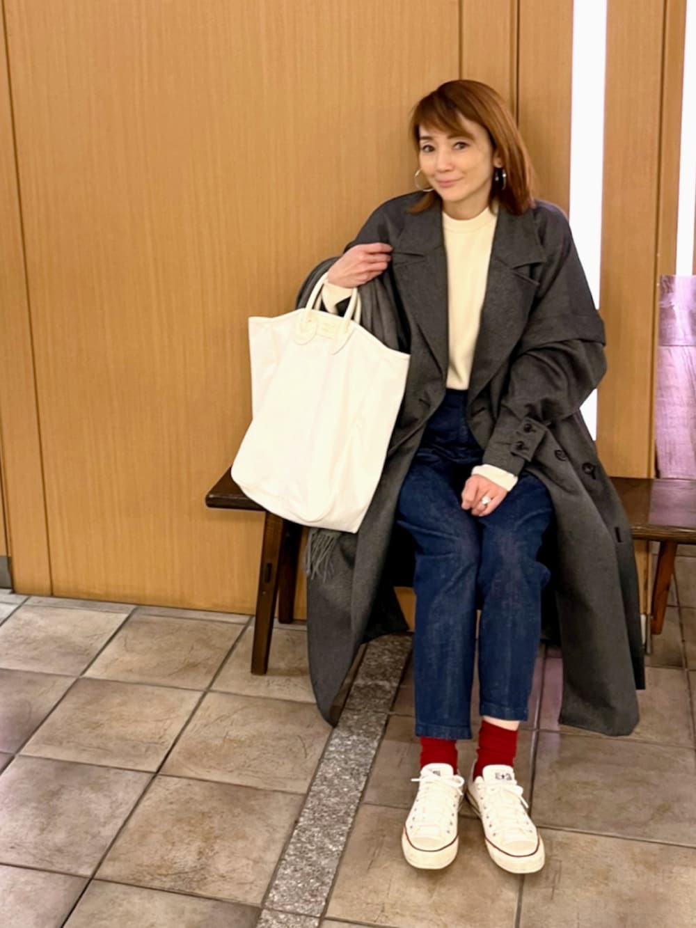 ブルー系のデニムパンツ、ホワイト系のニット/セーター、ホワイト系のトートバッグを着用したレディースの冬コーディネートの3枚目の写真