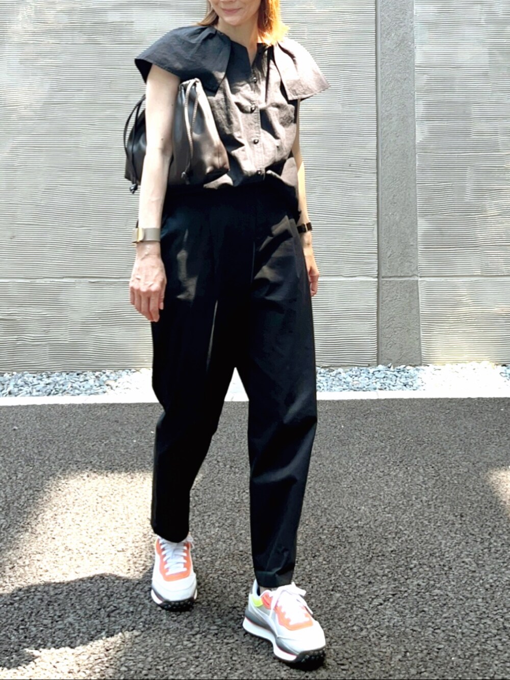 グレー系のスニーカー、ブラウン系のハンドバッグ、ブラック系のシャツ/ブラウスを着用したレディースの夏コーディネートの2枚目の写真