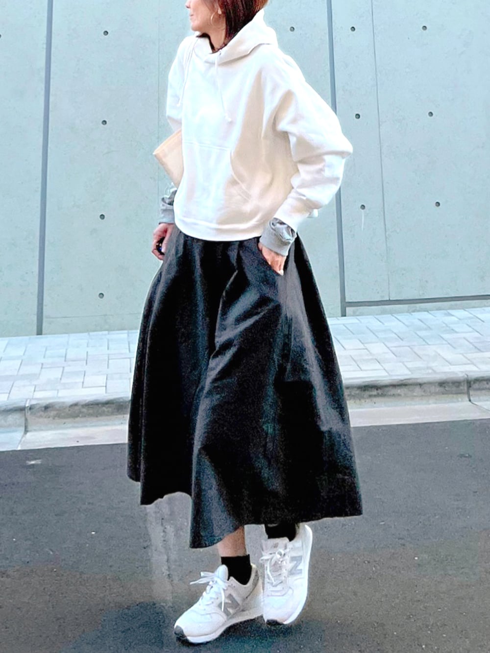 グレー系のスカート、グレー系のTシャツ/カットソー、ホワイト系のパーカーを着用したレディースの秋コーディネートの2枚目の写真