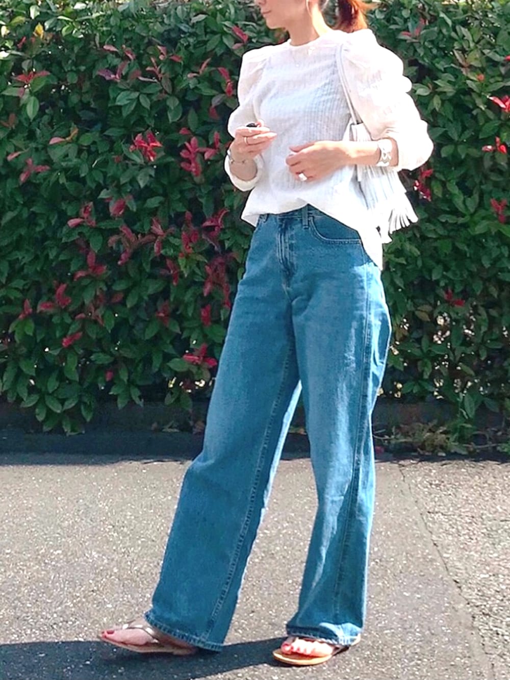 ブルー系のデニムパンツ、ホワイト系のシャツ/ブラウス、ゴールド系のサンダルを着用したレディースの夏コーディネートの2枚目の写真