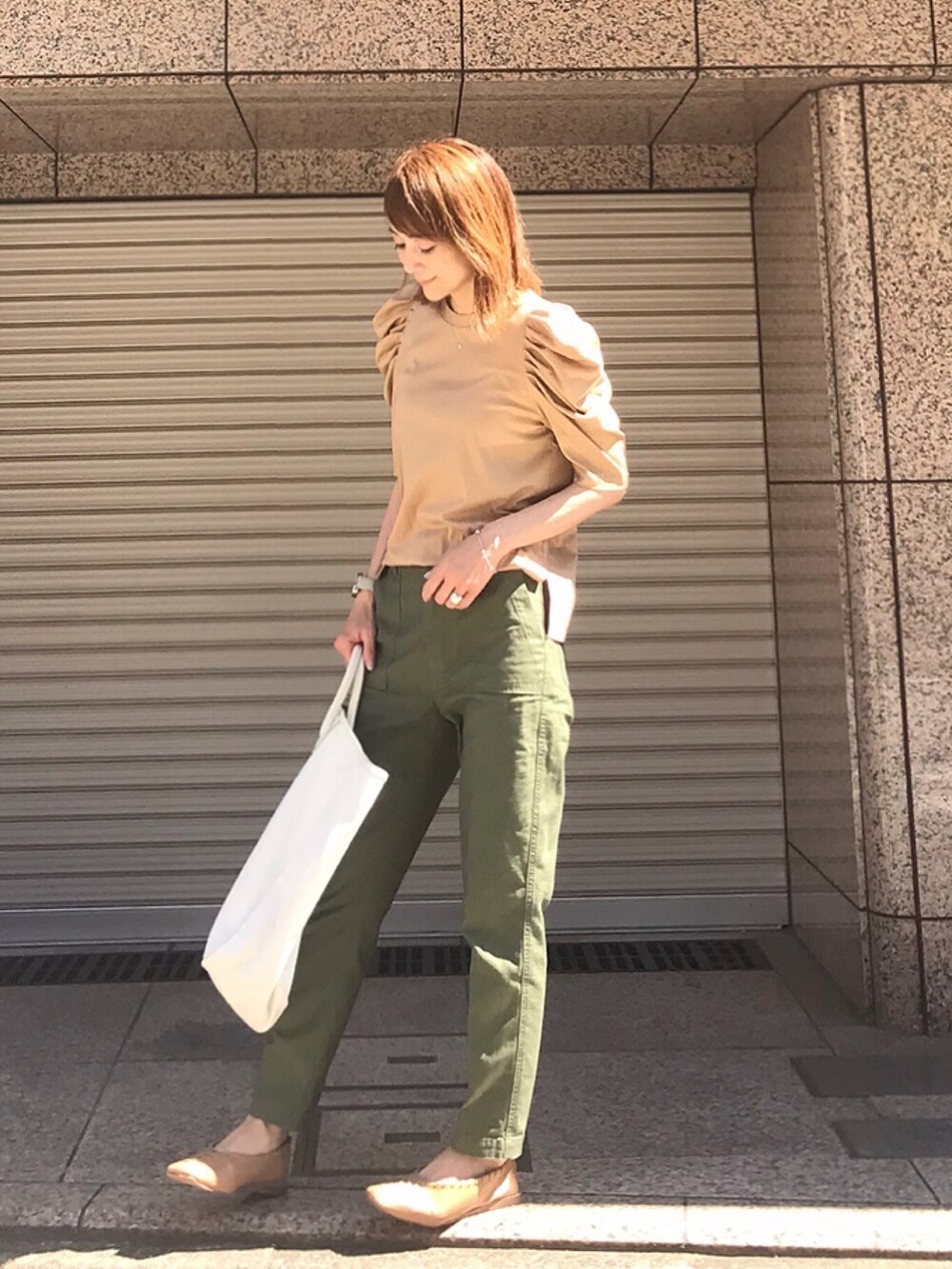 ベージュ系のTシャツ/カットソー、ベージュ系のパンプス、ホワイト系のトートバッグを着用したレディースの夏コーディネートの2枚目の写真