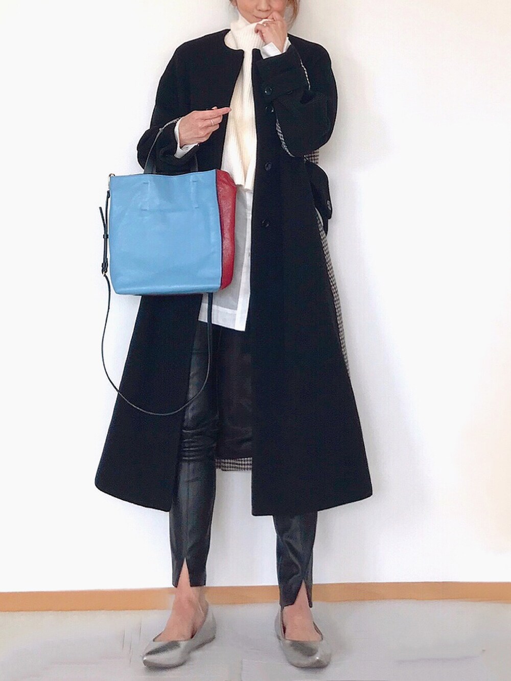 レッド系のトートバッグ、ホワイト系のニット/セーター、ホワイト系のシャツ/ブラウスを着用したレディースの冬コーディネートの2枚目の写真