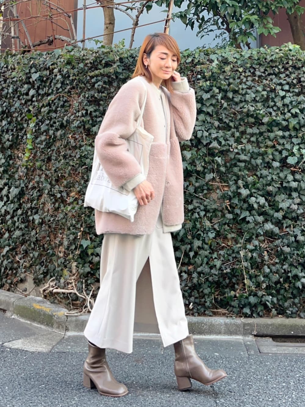 ベージュ系のその他アウター、ホワイト系のトートバッグ、ベージュ系のワンピースを着用したレディースの冬コーディネートの2枚目の写真