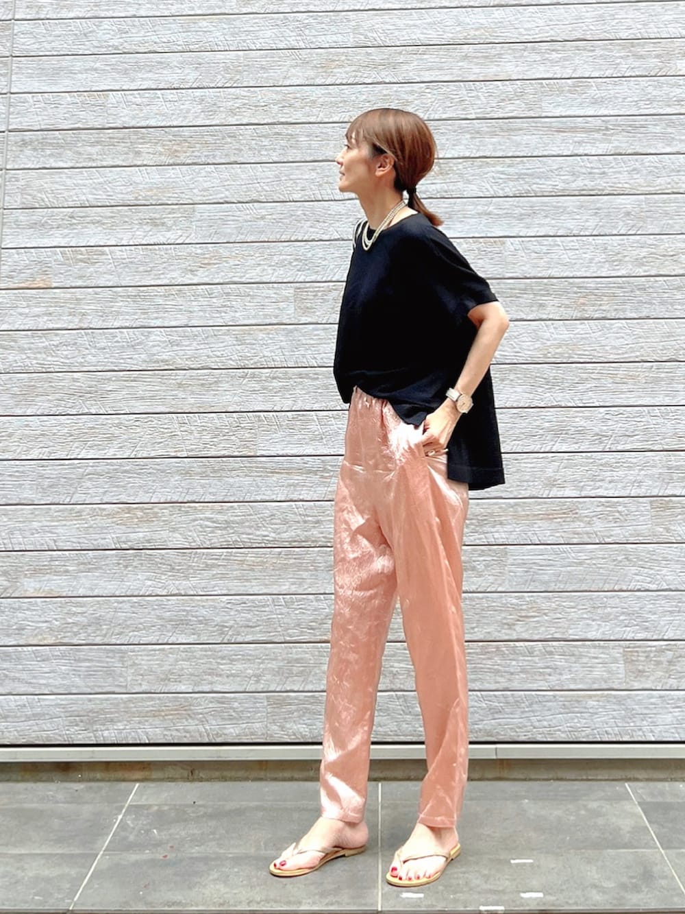 ブラック系のニット/セーター、グレー系のトートバッグ、ゴールド系のサンダルを着用したレディースの夏コーディネートの2枚目の写真