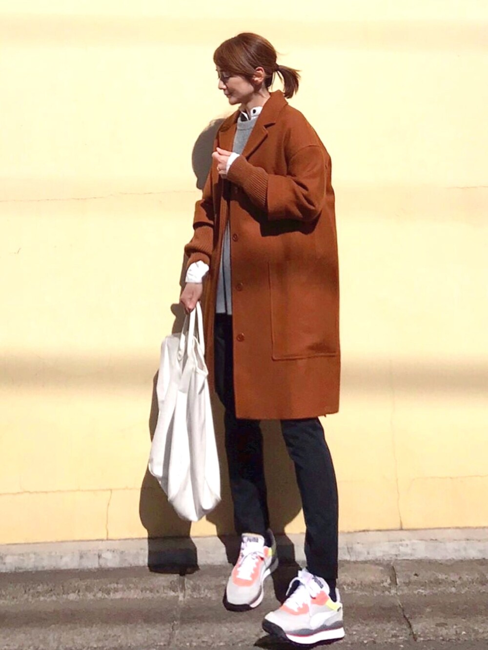 オレンジ系のジャケット/アウター、グレー系のスニーカー、ホワイト系のシャツ/ブラウスを着用したレディースの冬コーディネートの2枚目の写真